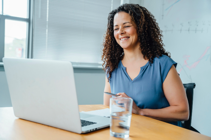 Mixed race businesswoman smiling at laptop