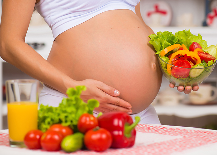 Mujer embarazada y frutas alrededor