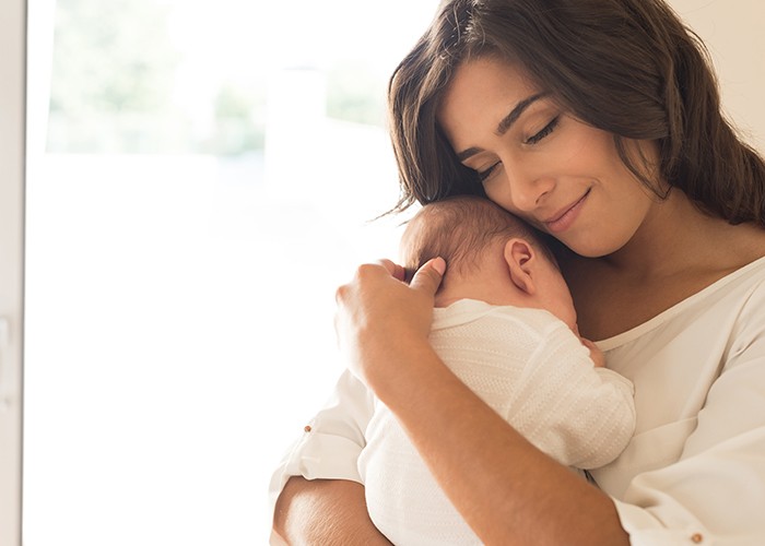 Mujer con niño recién nacido en los brazos