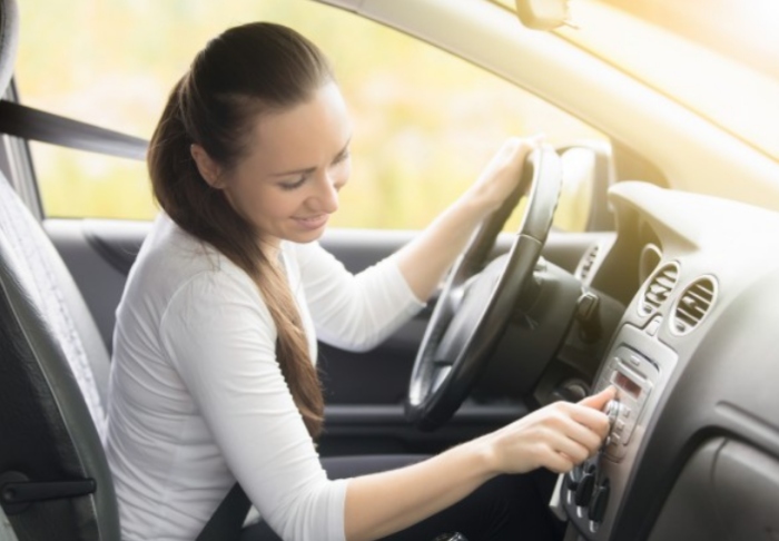 Mujer sentada en auto prendiendo la radio