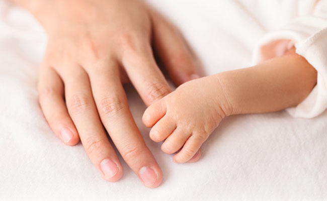Bebé recién nacido agarrando el dedo de su madre