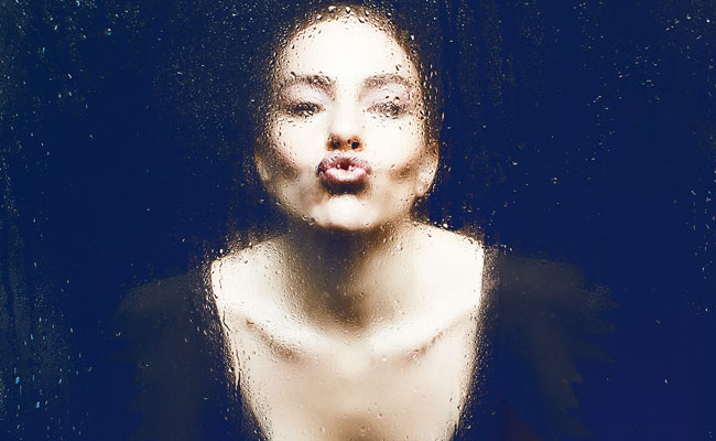 Mujer besando un vidrio empañado