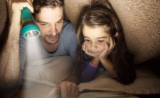 Padre leyéndole cuento a su hija 